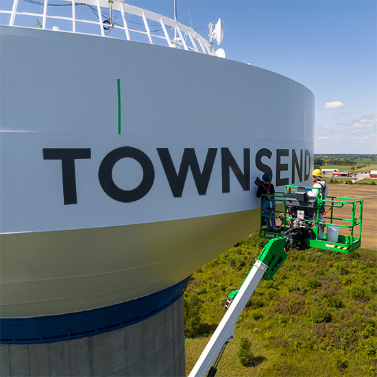 Workers painting protective coating to water tower